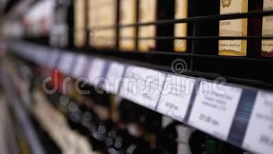 在超市里卖酒精。 一排排装着标价标签的瓶装葡萄酒在模糊的商店橱窗上